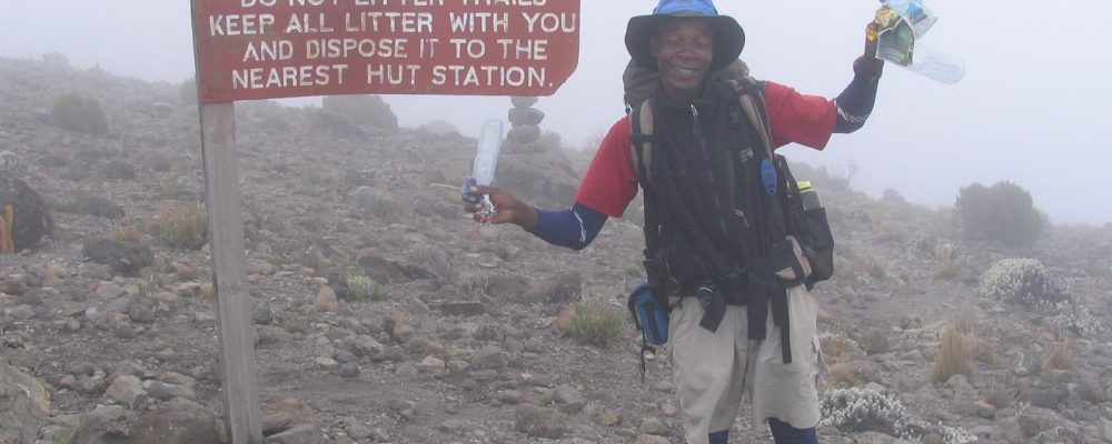 SENE guide picking up trash on Kilimanjaro